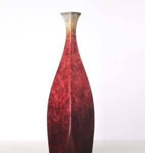 Tall slender vase with a faceted body and deep red marbled finish fading to a pale neck