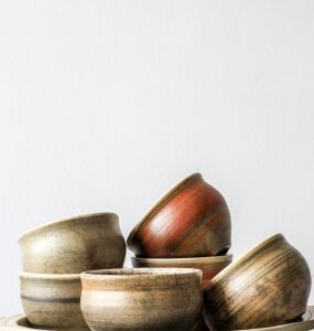 Small rustic bowls in brown, rust and sand glazes stacked on a shallow round tray